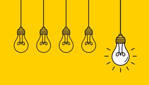 Hanging light bulbs with one glowing on yellow background. Concept of idea